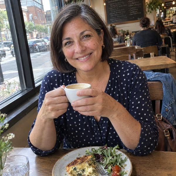 A woman in her late fifties at a table, natural window light, no product in hand